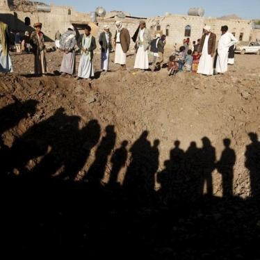 People stand around a crater caused by a Saudi-led air strike on the outskirts of Yemen's capital Sanaa, December 29, 2015. 