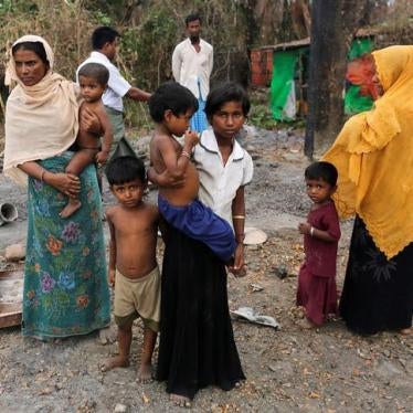 A family stands beside remains of a market which was set on fire, in Rohingya village outside Maungdaw, in Rakhine state, Myanmar on October 27, 2016. 