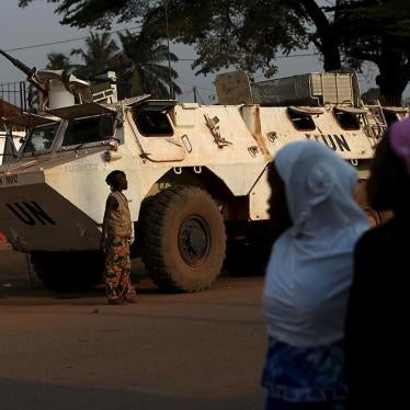 Women walk by a United Nations peacekeeping armored vehicle guarding the outer perimeter of a school used as an electoral center at the end of the presidential and legislative elections, in the mostly muslim PK5 neighborhood of Bangui.