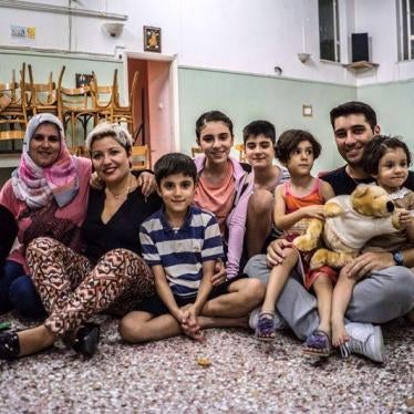 Falak from Syria – with her family Elin (2), Evin (4), Rudi (10), Mohamed (11) and Lava (13) – and Sperantza from Greece with her son Alexandros pose for a family photo in the temporary accommodation provided by the local Catholic parish in Aigaleo, Athen