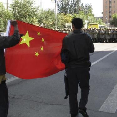Han Chinese residents hold a Chinese national flag as paramilitary policemen in riot gear block a road at the centre of Urumqi in China's Xinjiang Autonomous Region September 3, 2009.