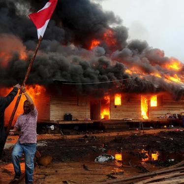 Two men hold the Indonesian flag as the compound of the Gafatar sect burns after being set on fire by local villagers, at Antibar village, West Kalimantan province, on January 19, 2016. 