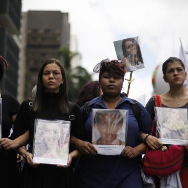 Durante uma marcha no Dia Internacional da Mulher em São Paulo, em 8 de março de 2014, mulheres seguram fotos de vítimas que morreram por violência doméstica.