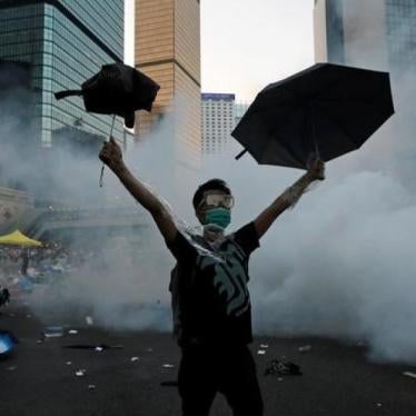 2014年9月28日，香港镇暴警察以催泪瓦斯驱散雨伞运动抗议民众后，一名男子高举雨伞示意。