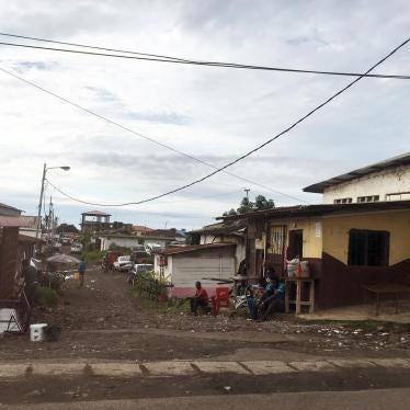 A wide shot of houses in a neighborhood of Malabo, Equatorial Guinea, with unpaved roads, one-storey houses, and trash 