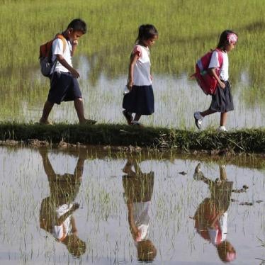 Grade school students are reflected in the water as they walk home after attending classes in Mogpog, Marinduque, the Philippines, on August 14, 2015.