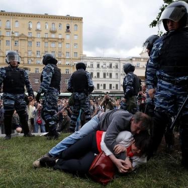 Yulia Galyamina and Nikolai Tuzhilin on the ground with riot police officials next to them. Moscow, July 2017