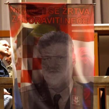 Bosnian Croats in Mostar, Bosnia and Herzegovina hang a flag displaying a portrait of General Slobodan Praljak and a message that reads "Your sacrifice will never be forgotten", as people pray and light candles for the convicted general.