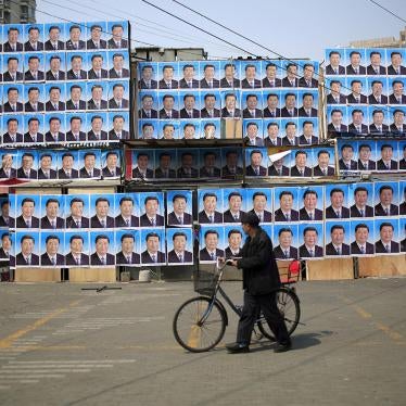A man with a bicycle walks past a building covered in posters of Chinese President Xi Jinping in Shanghai, March 26, 2016. 