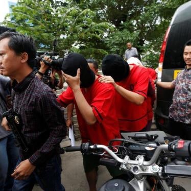 After a weekend raid on a sauna popular among gay men, a plainclothes policeman holds a rifle as he escorts several men during a police investigation in Jakarta, Indonesia