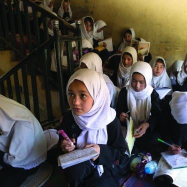 Girls sit for lessons on a stairwell inside a school building.