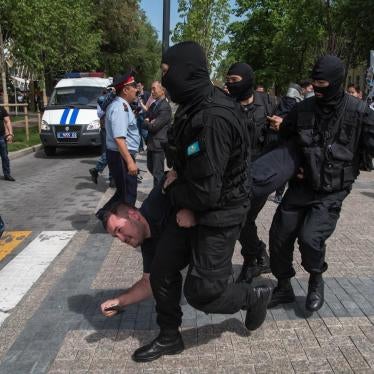 Masked law enforcement officers detain protester at a May 10 rally in Almaty, Kazakhstan.