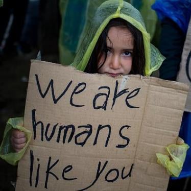 A girl holds a placard during a protest held by migrants and refugees to call for the reopening of the borders at a makeshift camp at the Greek-Macedonian border near the village of Idomeni 