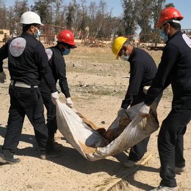 Members of the First Responders Team in Raqqa city, Syria exhume a body from a mass grave at the al-Rashid playing field.