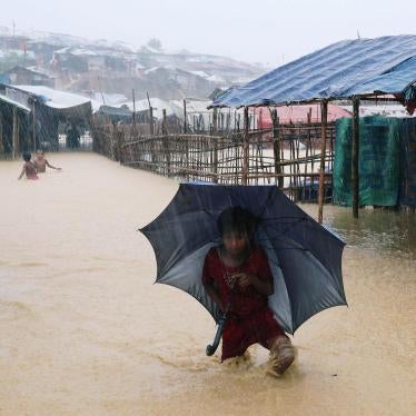 A Rohingya refugee girl walks along the water as the Kutupalong-Balukhali Expansion Camp floods during heavy rain in Cox's Bazar, Bangladesh, July 2018. 