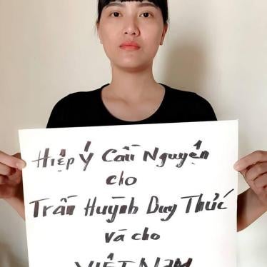 Huynh Thuc Vy holds a sign that reads "Praying for Tran Huynh Duy Thuc and for Vietnam. Sept 12, 2018".
