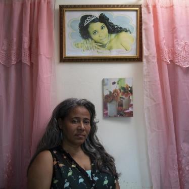 Rosa Hernández stands in her home below a photo of her daughter, Rosaura Almonte Hernández, who died in 2012 at age 16.