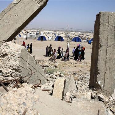 Displaced Iraqis walk past destroyed buildings next to Hammam al-Alil camp for internally displaced people south of Mosul on May 26, 2017, as government forces continue their offensive to retake the city of Mosul from Islamic State (ISIS). © 2017 Karim Sa