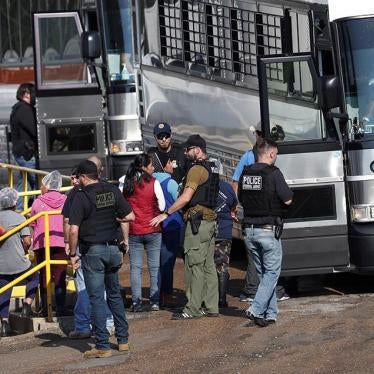 Workers are escorted onto a bus for transportation to a processing center following a raid by US immigration officials