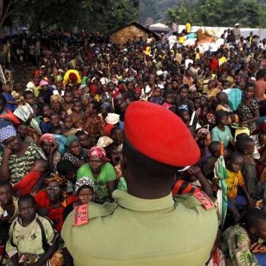 A Tanzanian policeman watches over as Burundian refugees gather on the shores of Lake Tanganyika in Kagunga village in Kigoma region in western Tanzania, where they wait for transport to Kigoma township, May 17, 2015.