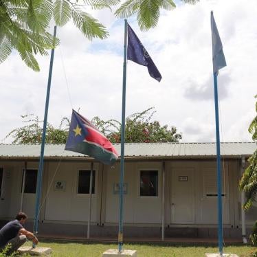 A man raises a flag outside the IOM compound in South Sudan