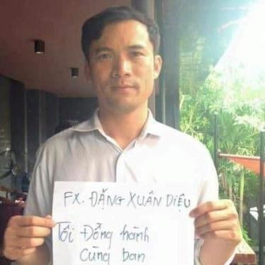 Nguyen Nang Tinh supporting the then political prisoner Dang Xuan Dieu holding a sign that reads, "Fx Dang Xuan Dieu – I accompany you." 