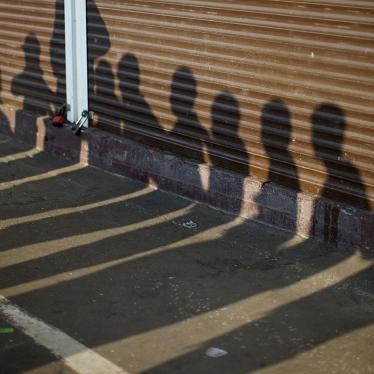 Shadows of people detained by Russian police, suspected of violating immigration rules during an action seen on containers at a street market in Moscow, Russia, August 7, 2013. © AP Photo/Alexander Zemlianichenko