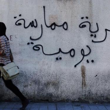A Tunisian woman walks past a graffiti that reads "Freedom is a daily practice" in Tunis April 26, 2011.