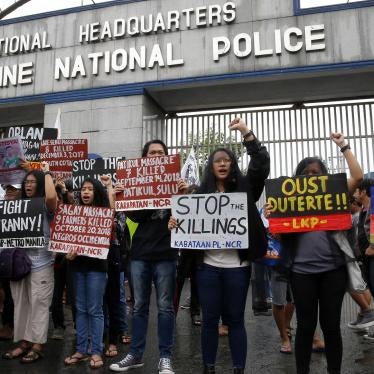 Veiled protesters, mostly relatives of victims of alleged extra-judicial killings, display placards during a protest outside the Philippine military and police camps