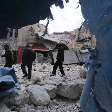 People walk past destruction from government airstrikes in the town of Ariha, in Idlib province, Syria, January 15, 2020.