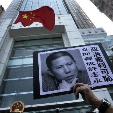 A demonstrator raises a poster of Xu Zhiyong during a protest against his sentencing, Hong Kong, January 27, 2014.