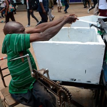 A man using a wheelchair is pictured washing his hands in a public water tap in Nairobi, Kenya, as a preventive measure against COVID-19, March 22, 2020.