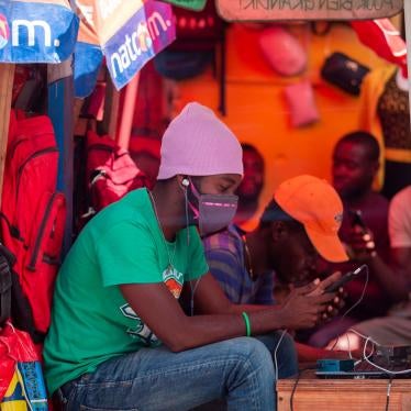 A street seller checks his phone while wearing a mask to protect himself from the spread of the new coronavirus, in Port-au-Prince, Haiti, Monday, March 23, 2020.