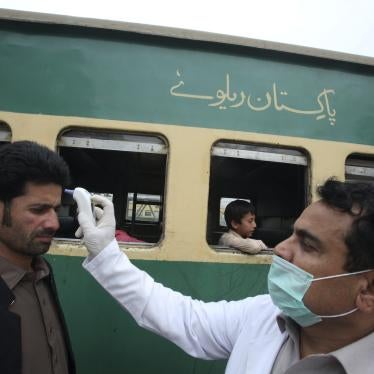 A volunteer checks the temperature of passengers arriving at a railway station in Peshawar, Pakistan, March 17, 2020.