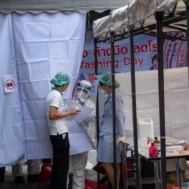 A man in a Hazmat suite talks with a nurse at a makeshift screening facility outside Rajadamnern boxing stadium in Bangkok, Thailand, March 19, 2020.