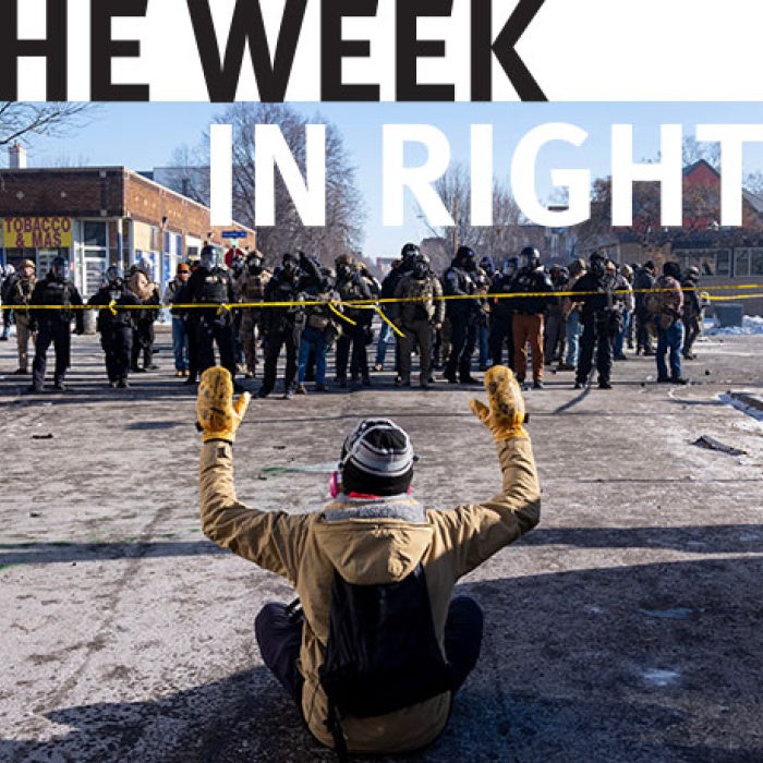 A protester sits on the street with his arms up in front of federal agents and Minneapolis Police on W. 27th St and Nicollet Avenue in south Minneapolis after Alex Pretti was fatally shot by federal agents in the area 