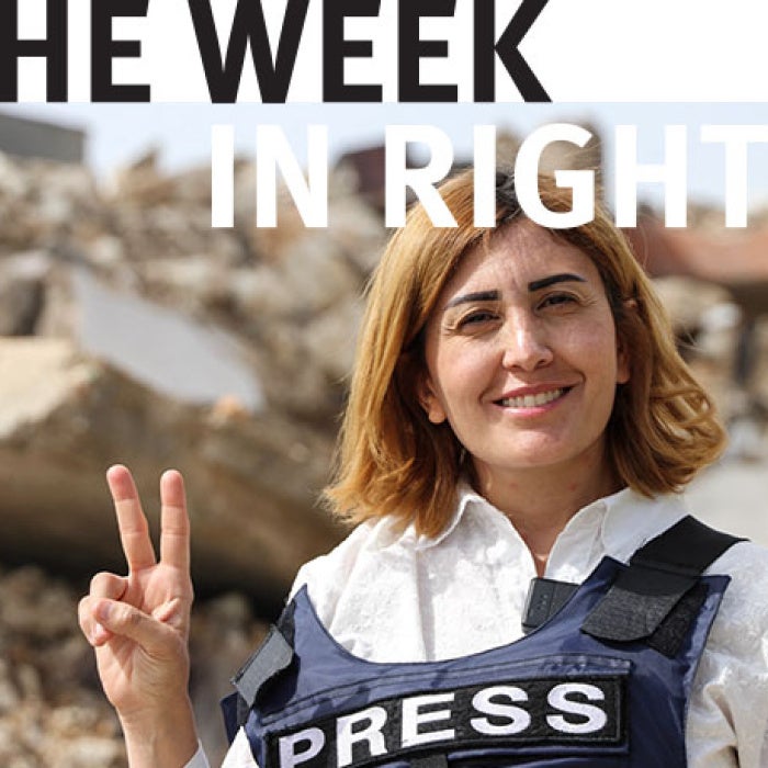 Journalist faces camera and raises two fingers to form a peace sign.